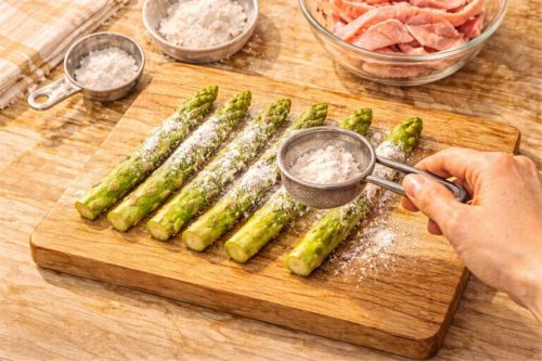 アスパラに茶こしで小麦粉を薄くまぶしているシーン