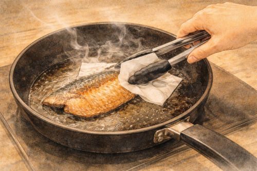 焼いているホッケから出た余分な脂や水分を取り除いているシーン