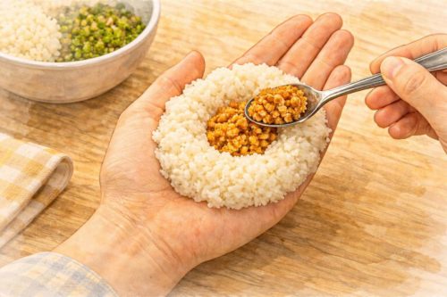 ごはんの中央にくぼみをつくり、そこに鶏そぼろを入れているシーン