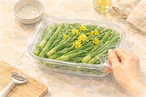 耐熱容器に入ったアスパラ菜にラップをかけているシーン